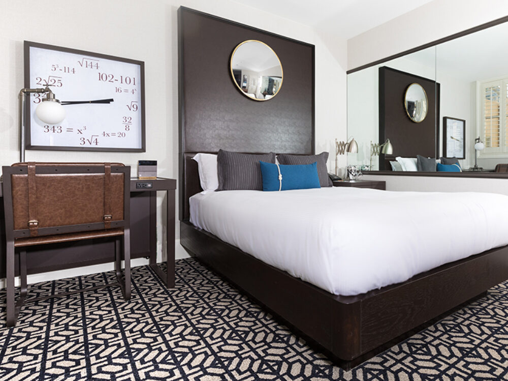 Cozy One Full Room at Harbor Court Hotel, featuring a full-size bed with elegant bedding, a working desk with a leather chair, and sophisticated wall art