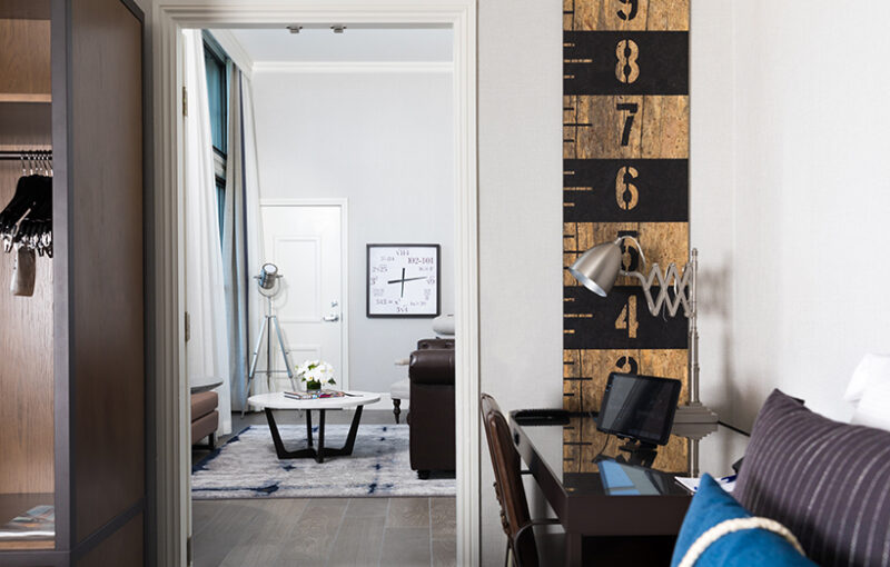 Another view of the Skyline Waterfront Penthouse Suite at Harbor Court Hotel, highlighting a workspace with a decorative lamp and a partial glimpse into the living room with stylish furnishings.